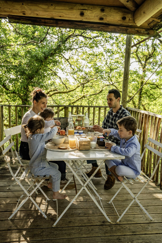 Famille prenant le petit déjeuner sur la terrasse d'une cabane perchée en Dordogne