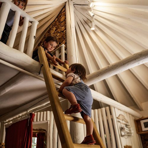 Enfants jouant sur échelle dans une cabane ronde du Domaine Périgord Vacances